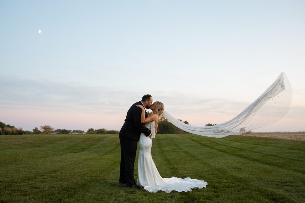 couple kissing at sunset with veil